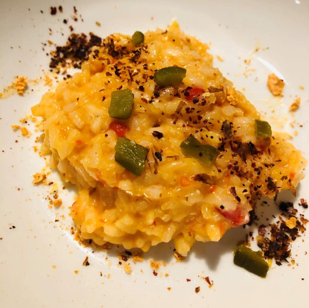 The finished roasted pepper risotto with chopped jalapeno and ground pepper skins and ground grapefruit skin on top.