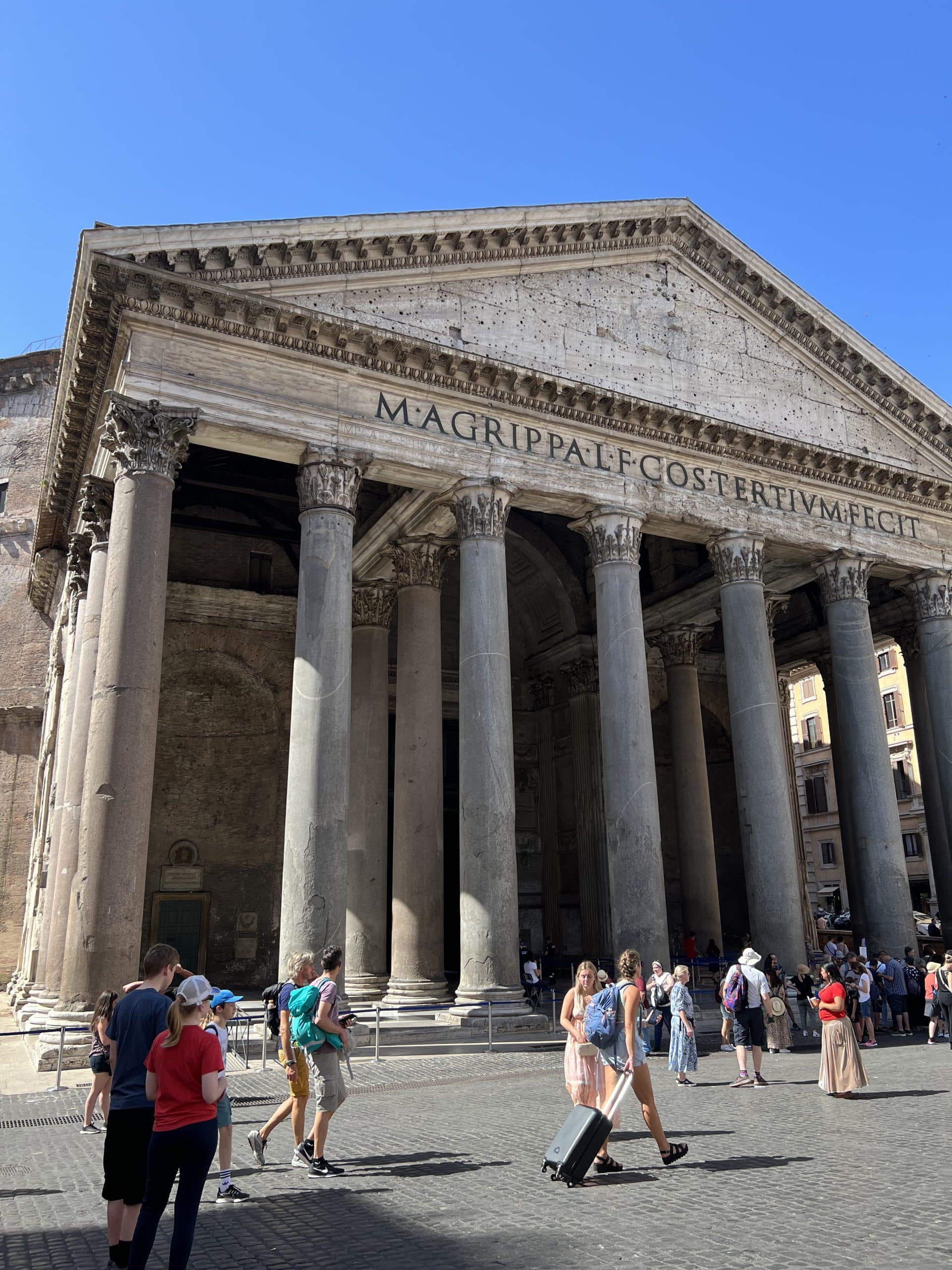 View of the pillars on the Pantheon in Rome. Tourists standing with maps and suitcases feeling overwhelmed and wondering are food tours in Italy worth it.