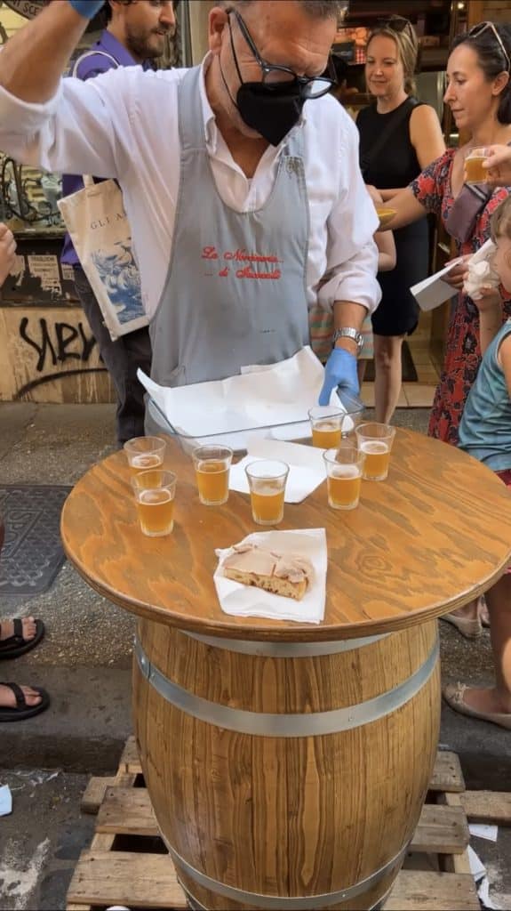 Chef at the norcineria serving beer and porchetta e pane in during the Twilight Trastevere Food Tour.