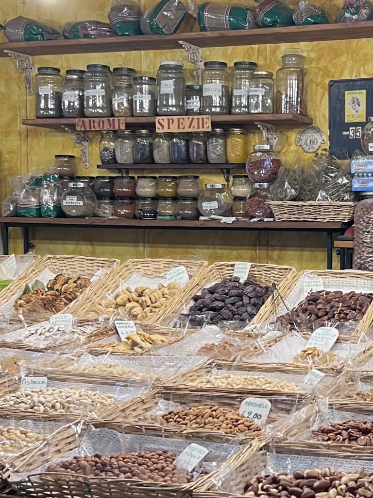 Baskets of nuts and dried fruits, shelves with spices at a stall at the Florence Central Market