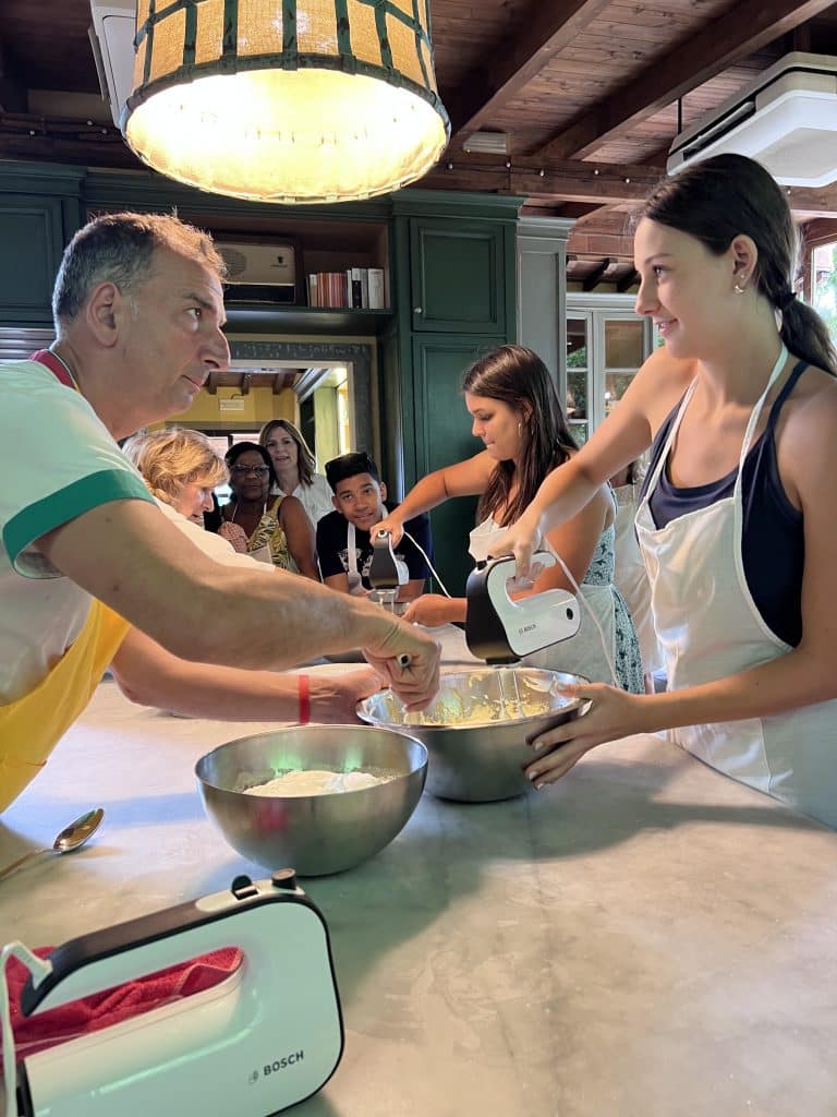 Students in cooking class beating eggs with beaters to make tiramisu.