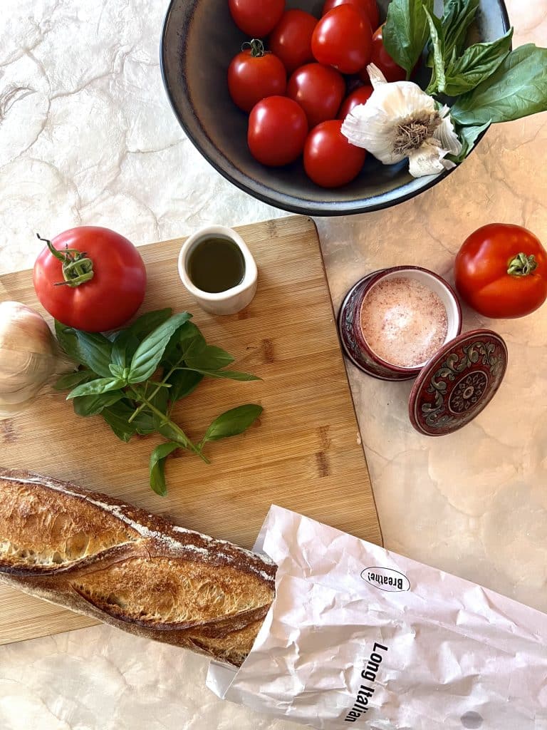 Tuscan Bruschetta recipe ingredients of rustic bread, tomatoes, basil, garlic, olive oil, and salt.