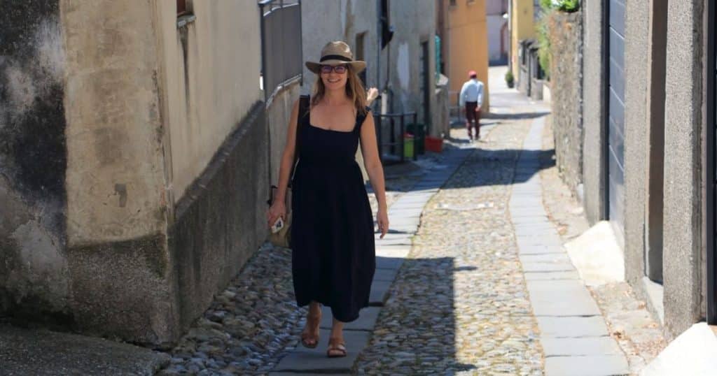 Woman walking up a narrow cobblestone street in a small Italian village on her ancestry tour.