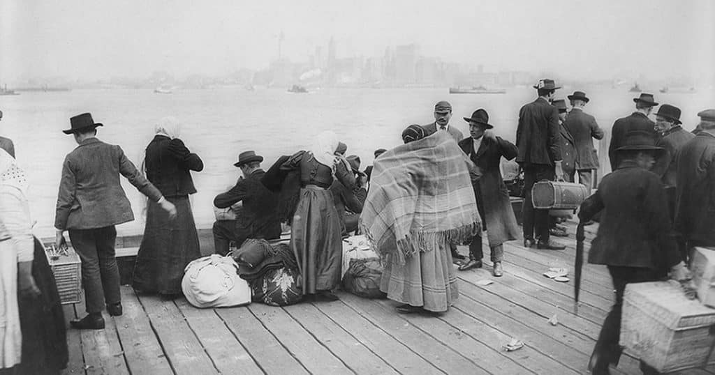 Black and white historical photo of Italian immigrants arriving in New York harbor in the late 1800s