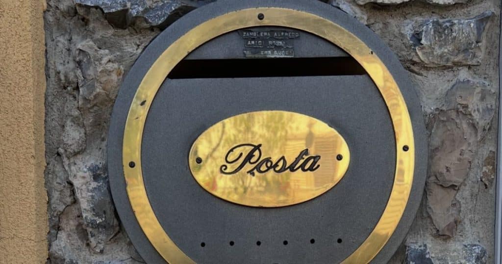 A vintage-style Italian mailbox labeled 'Posta' on a stone wall in the Bergamo valley