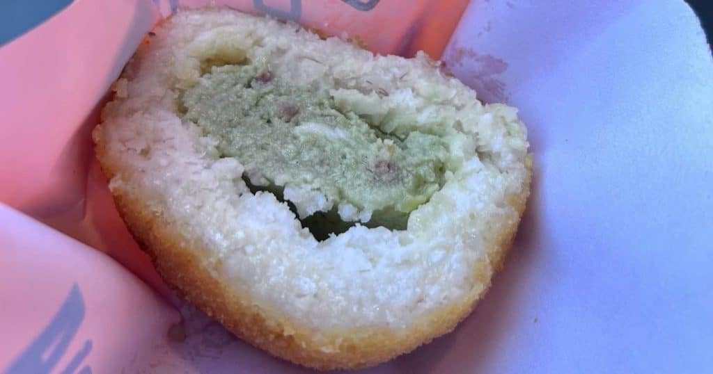 Cross-section of a pistachio arancino, showing the creamy green pistachio filling inside the crispy rice shell