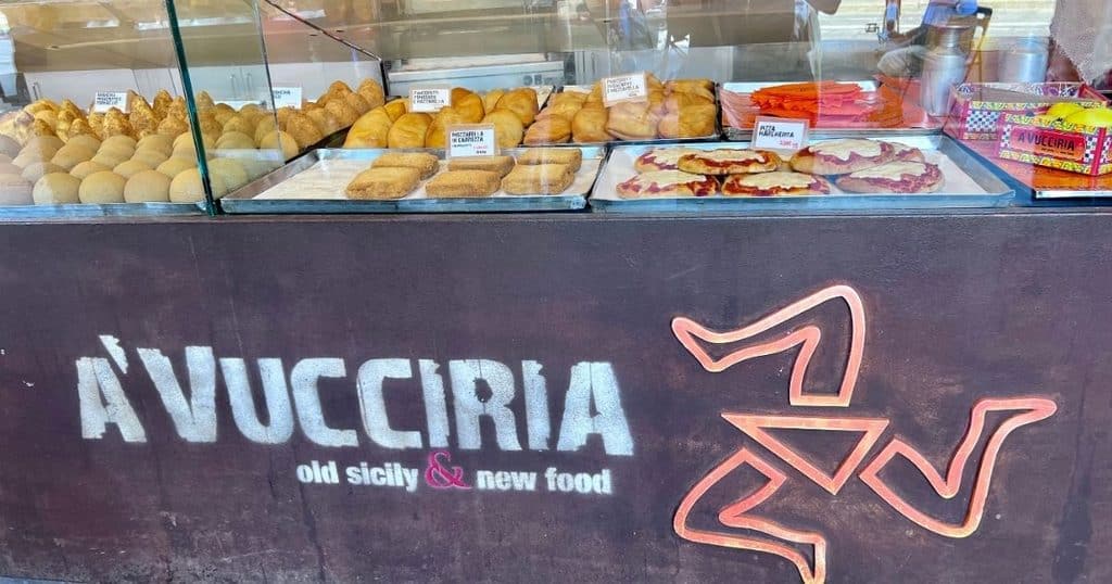 Display case of Sicilian street food at A'Vucciria, including arancini, panzerotti, and mozzarella in carrozza