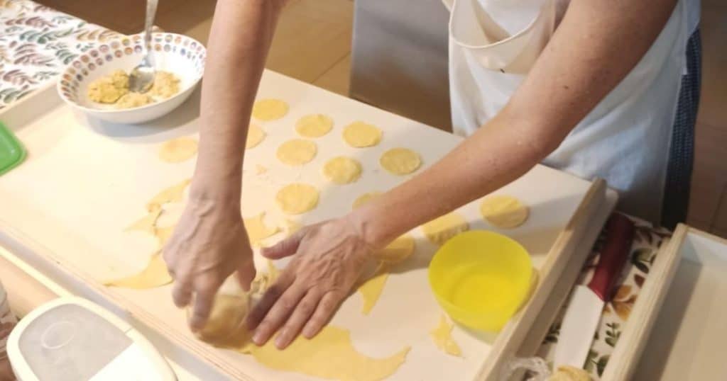 Pressing down with a glass jar on rolled out pasta dough to form circles for the Scarpinocc.