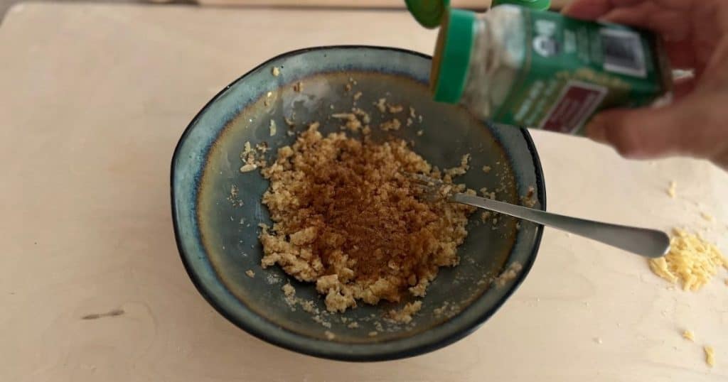 Hand sprinkling spices into the filling in a bowl.