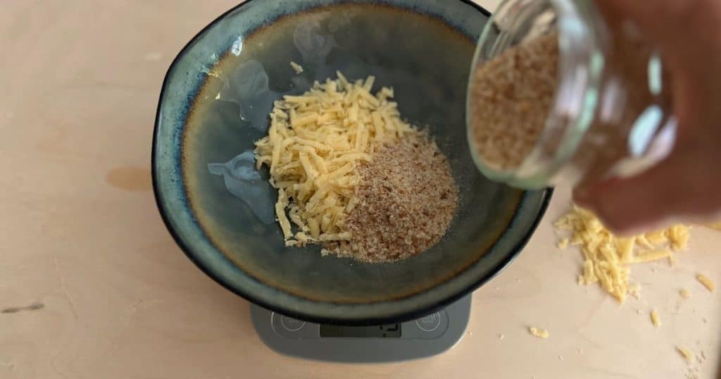 Grated parmesan and breadcrumbs in a bowl on a scale.