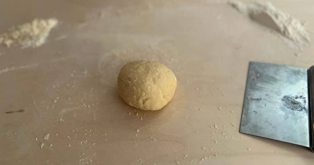 Ball of pasta dough with dough scraper.