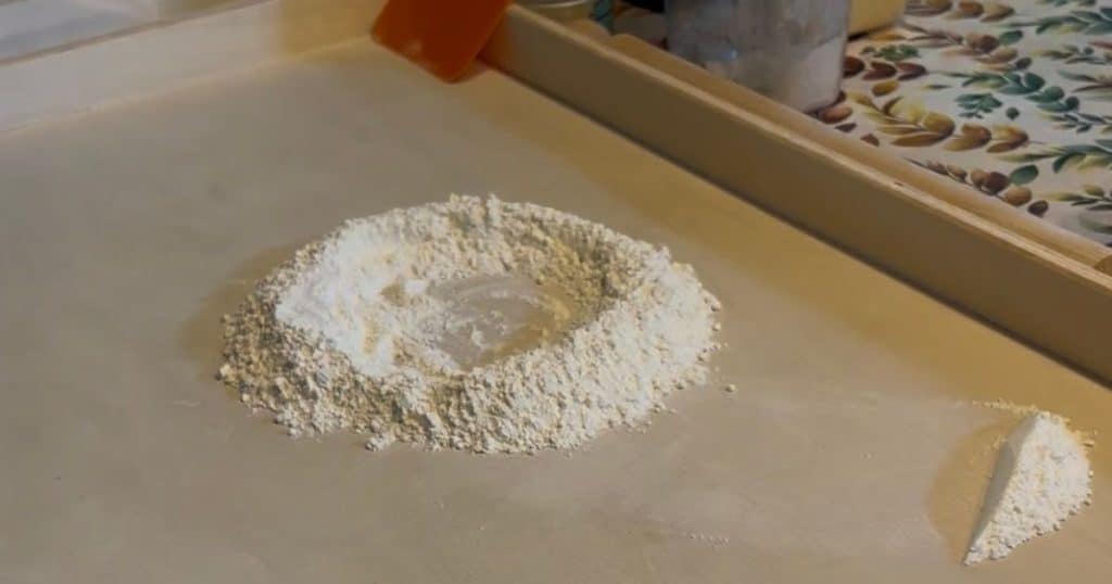 How to make scarpinocc. Mound of flour on a spianattoia with some flour to the side.